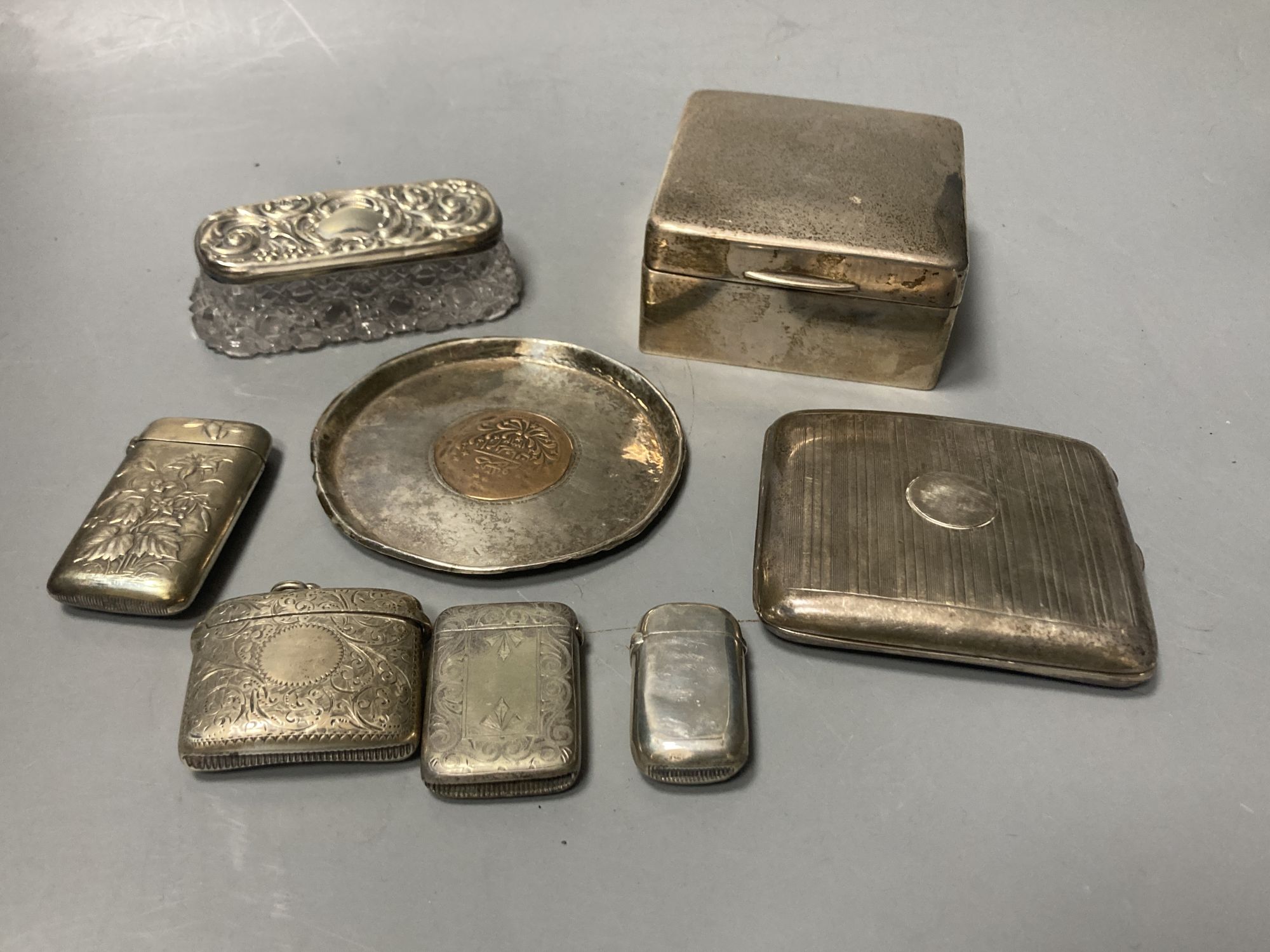 A silver cigarette box, silver cigarette case, four vestas including two silver, a continental dish and a toilet jar.